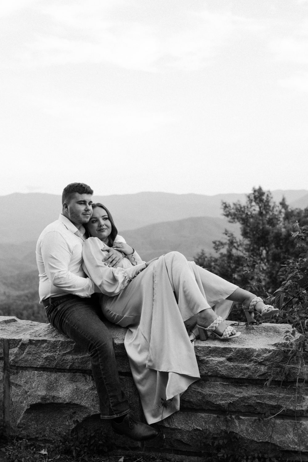 A couple sits on a ledge overlooking the Smoky Mountains in Tennessee