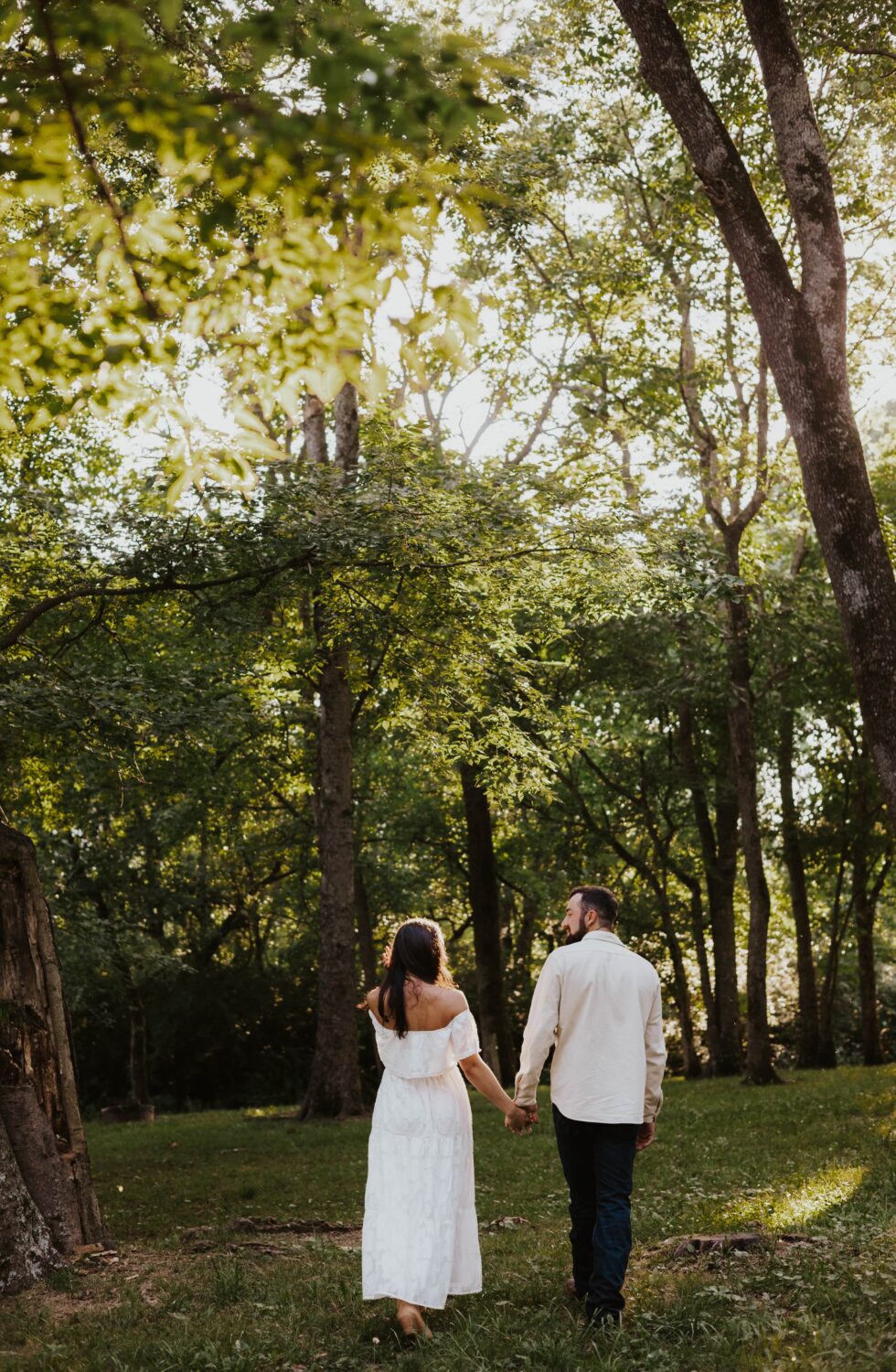 A couple holds hands together in the woods for an engagement session.
