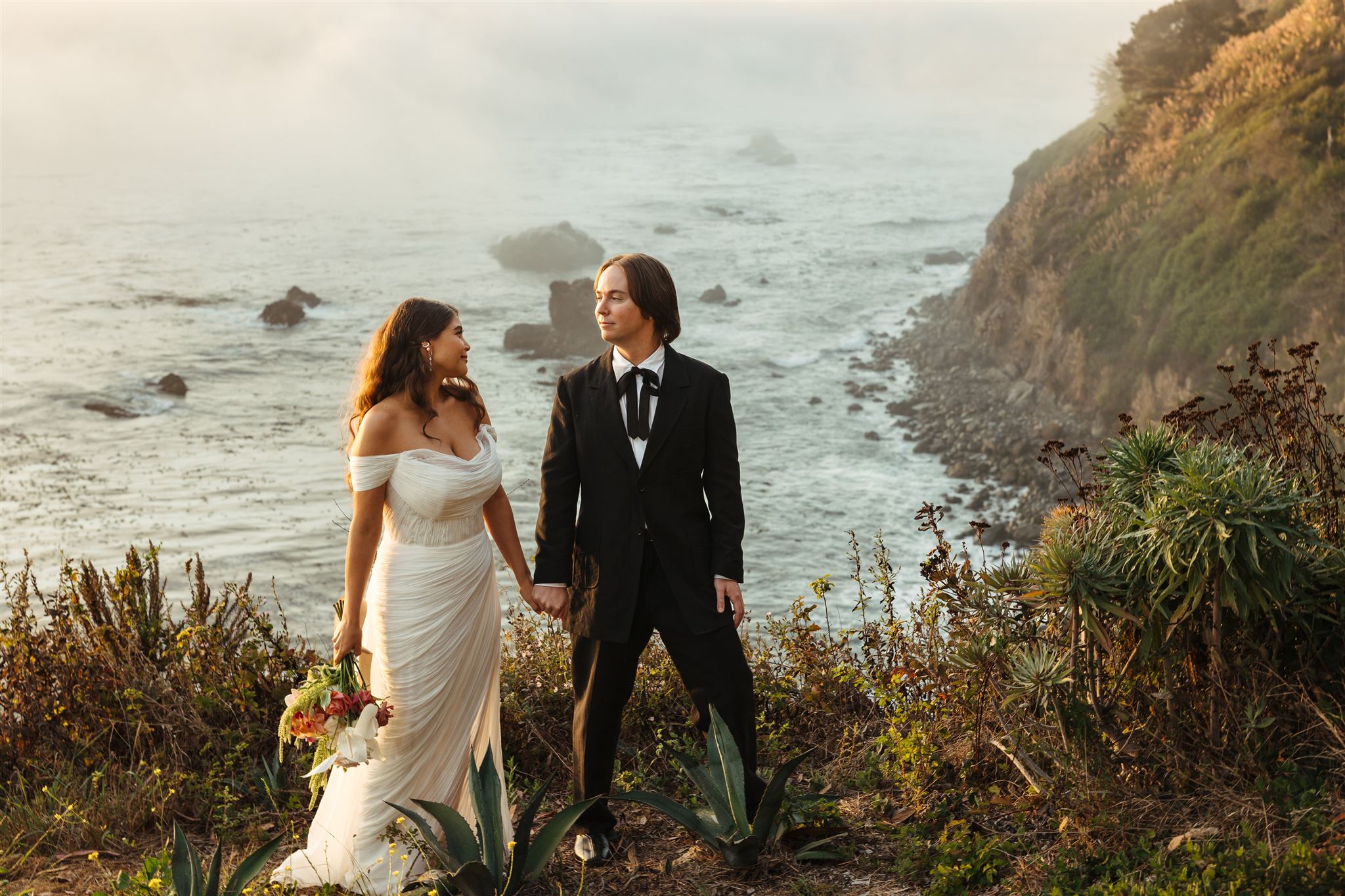 A couple holds hands at their wedding day at Wind & Sea estate in Big Sur, California.