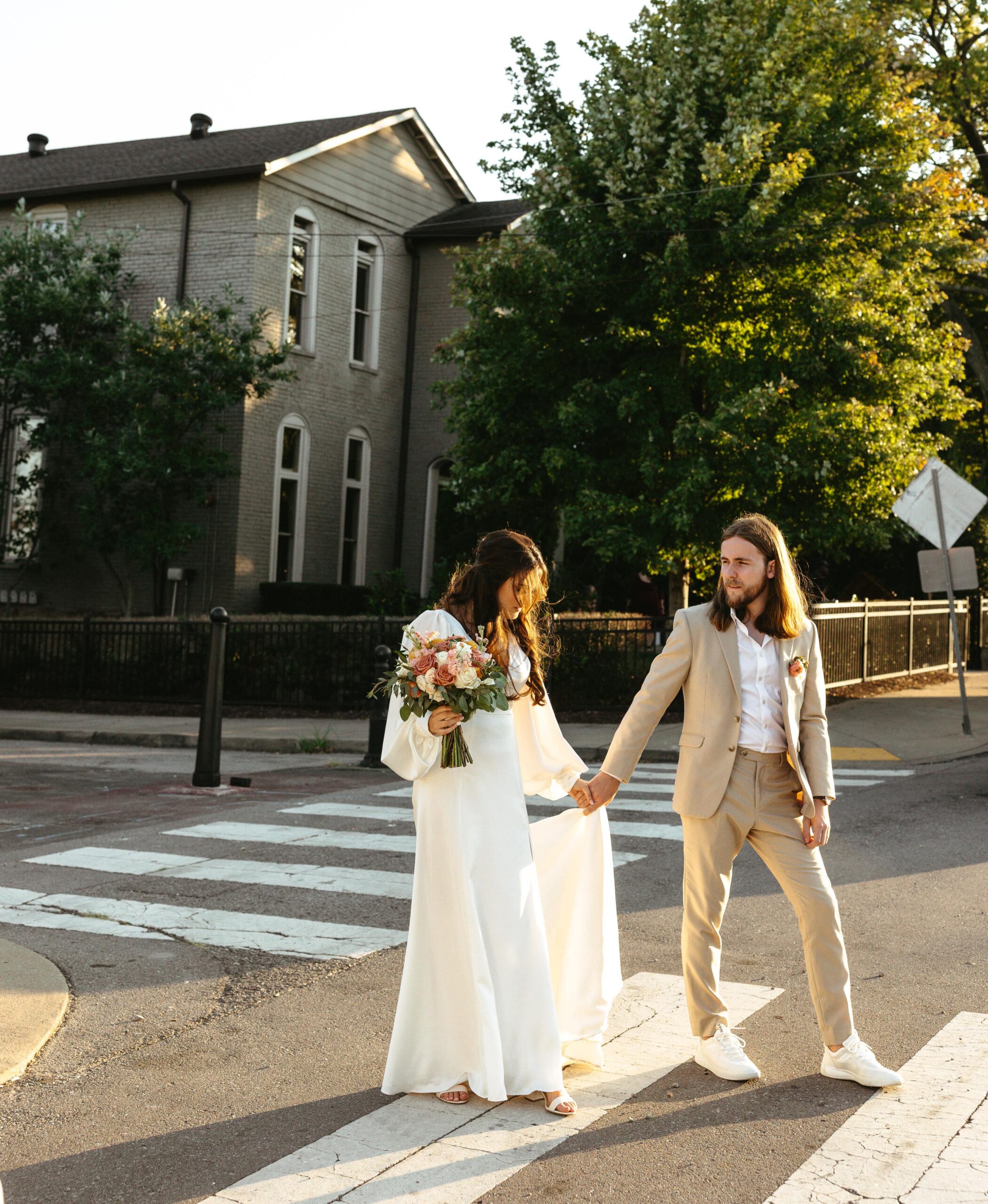 A bride and groom walk across a crosswalk in downtown Nashville.