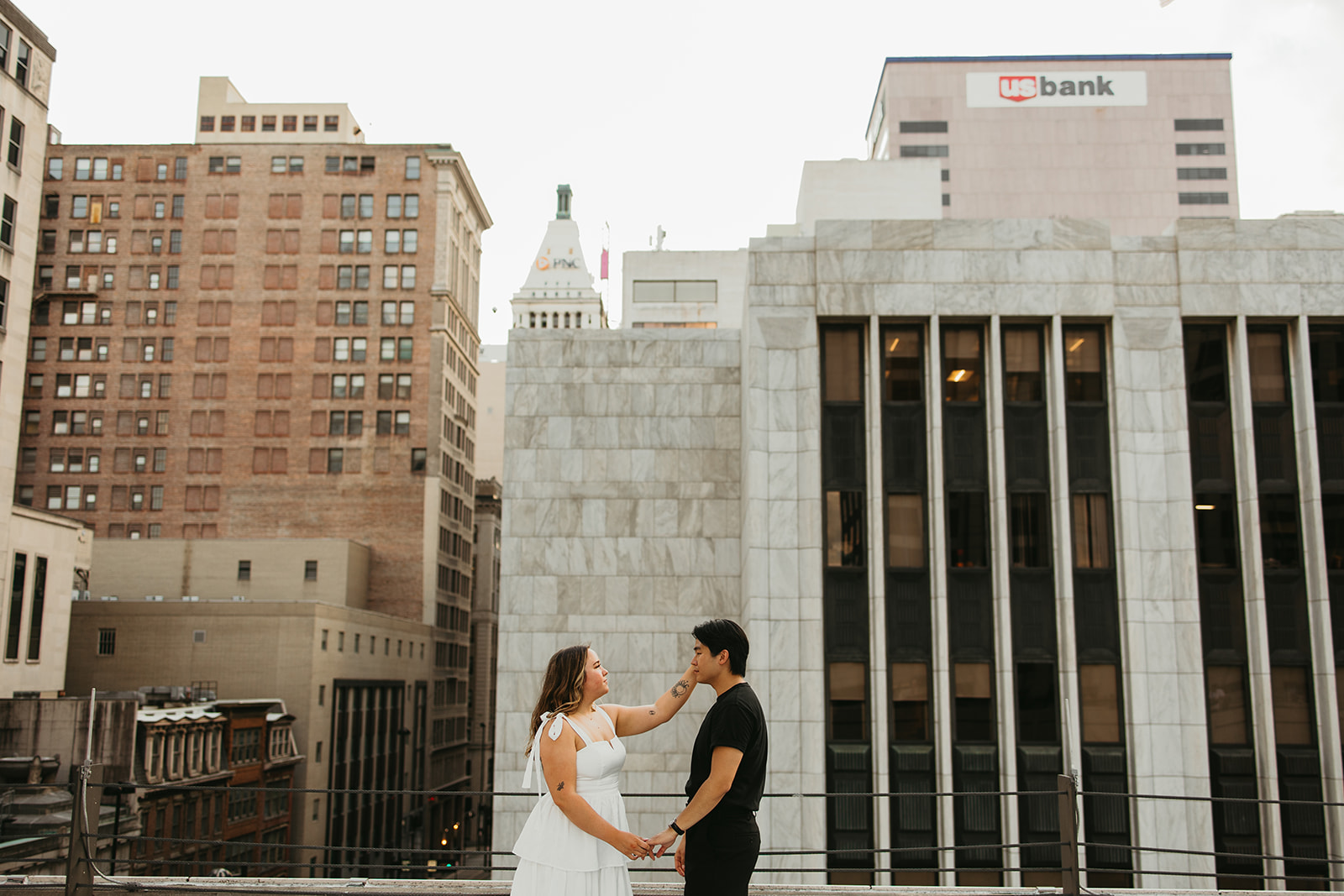 A couple smiles on a rooftop in Cincinnati for their engagement photos.